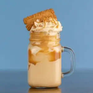 A creamy caramel milkshake topped with whipped cream and a biscuit, perfect for a sweet treat.